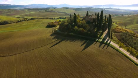 beautiful landscape scenery of tuscany in italy - farmhouse, cypress trees along white road - aerial view