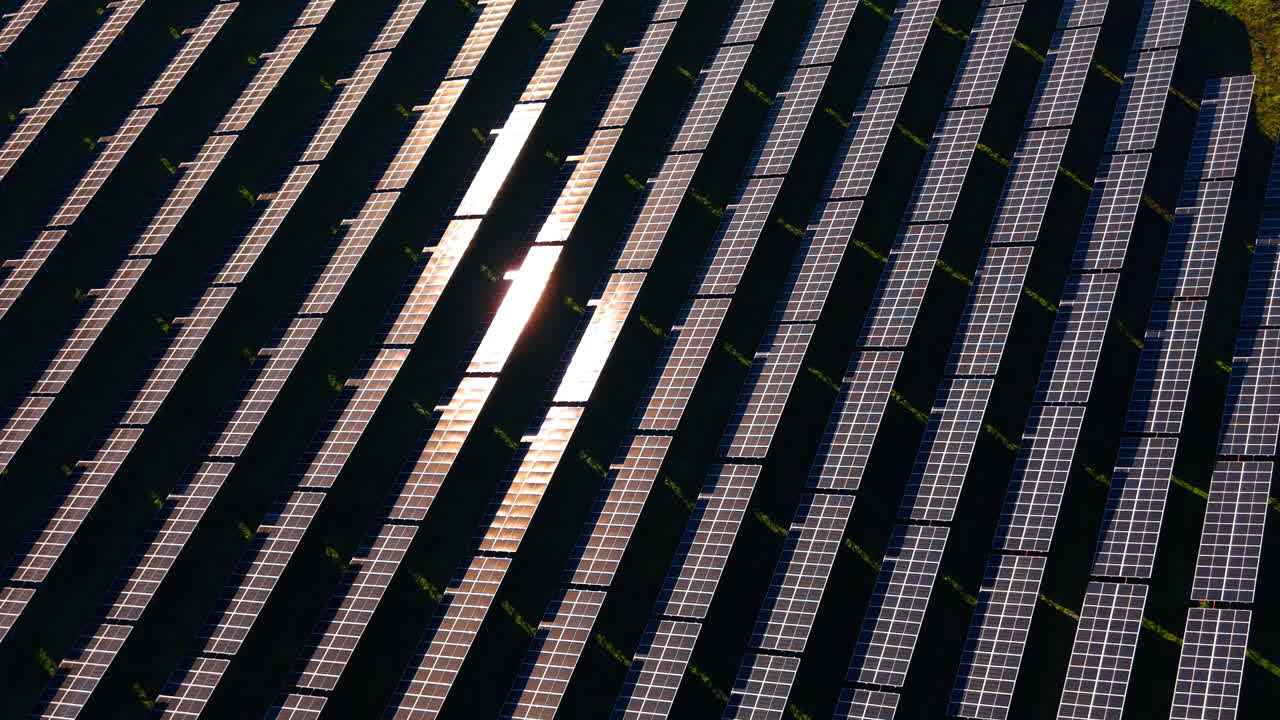 Motivo geometrico di pannelli solari con intenso bagliore solare. Inquadratura dall'alto di file fotovoltaiche diagonali con un forte riflesso della luce su diversi moduli