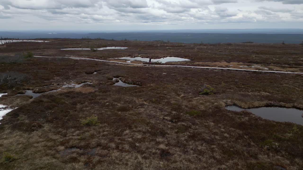 una mujer y su perro caminando por un sendero de montaña con lagos y nieve a su alrededor