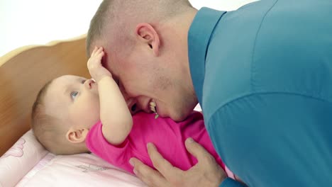 Cu-Cámara-Lenta-Padre-Joven-Juega-Con-Su-Pequeña-Y-Dulce-Hija-Que-Yace-Sobre-Una-Mesa