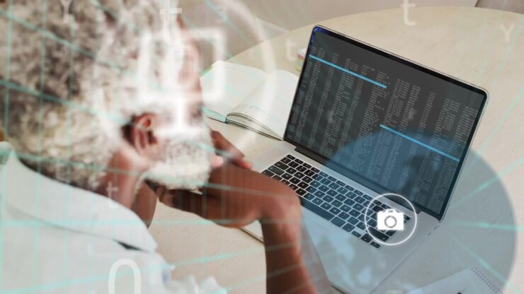 Ældre mand sidder ved bærbar computer, kodeoutput aktiverer overlejrende telefonchatikoner til IT-fejlfinding