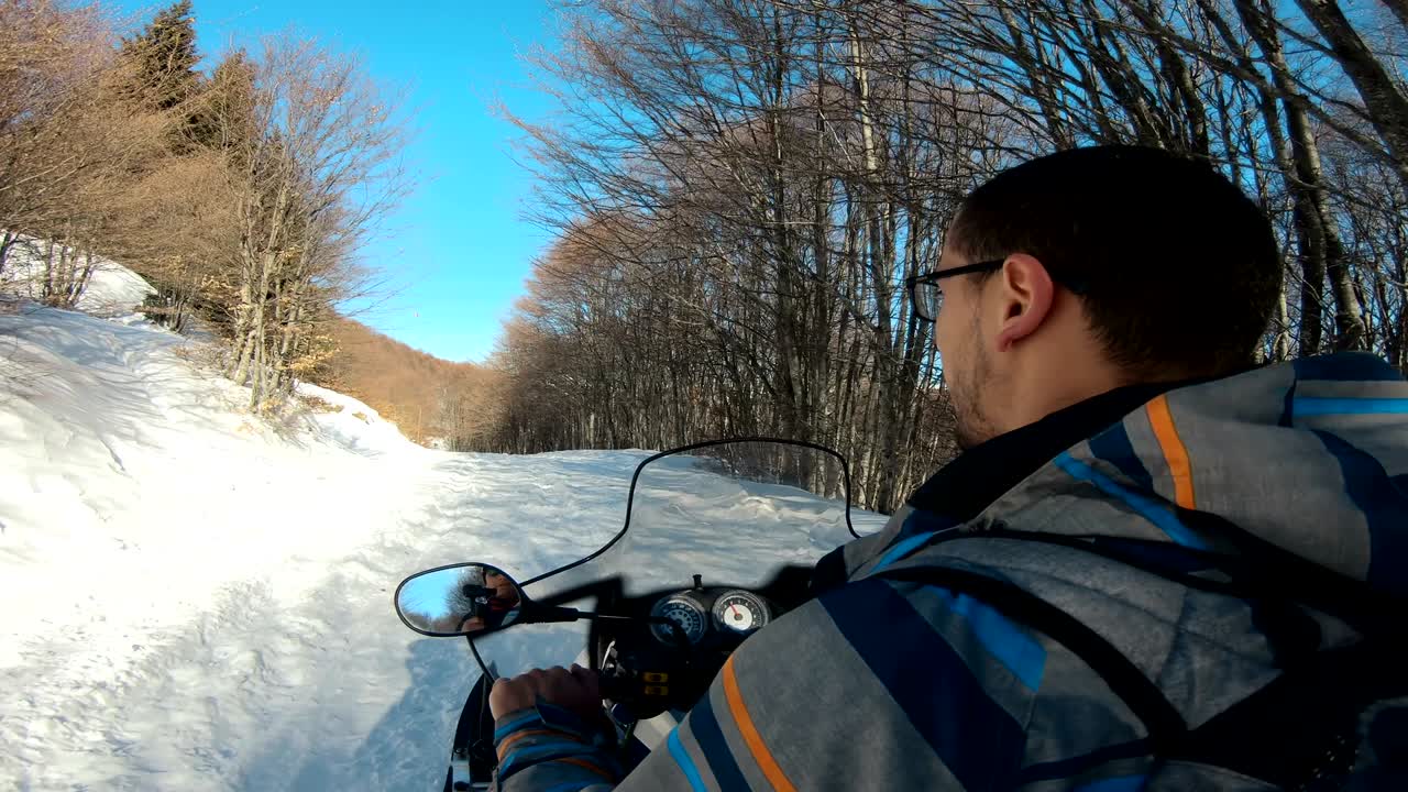 Man driving sports snowmobile in forest in a sunny day
