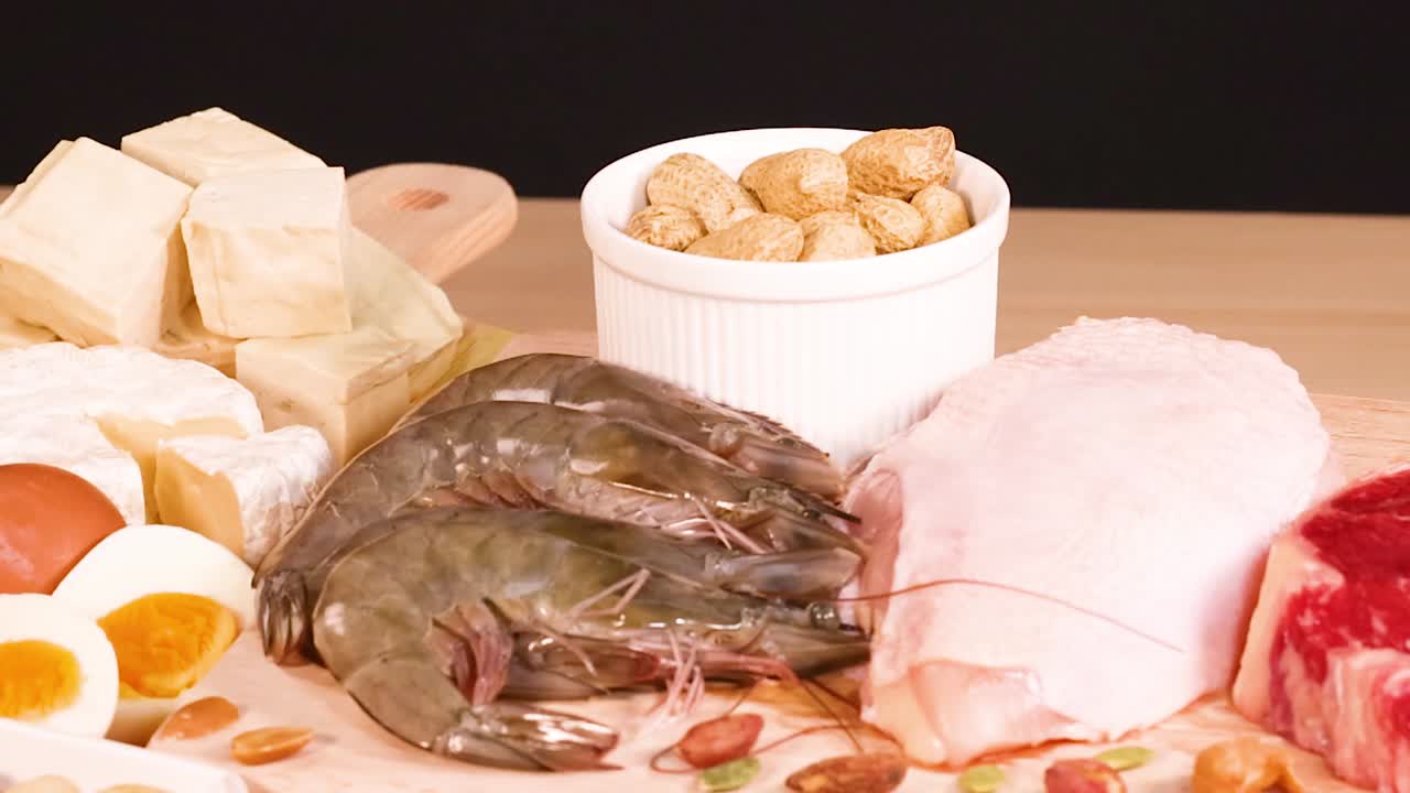 An array of protein sources including shrimp, nuts, and meats arranged on a wooden table.