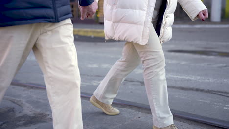 side view of a senior couple holding hands and walking down the street on a winter day