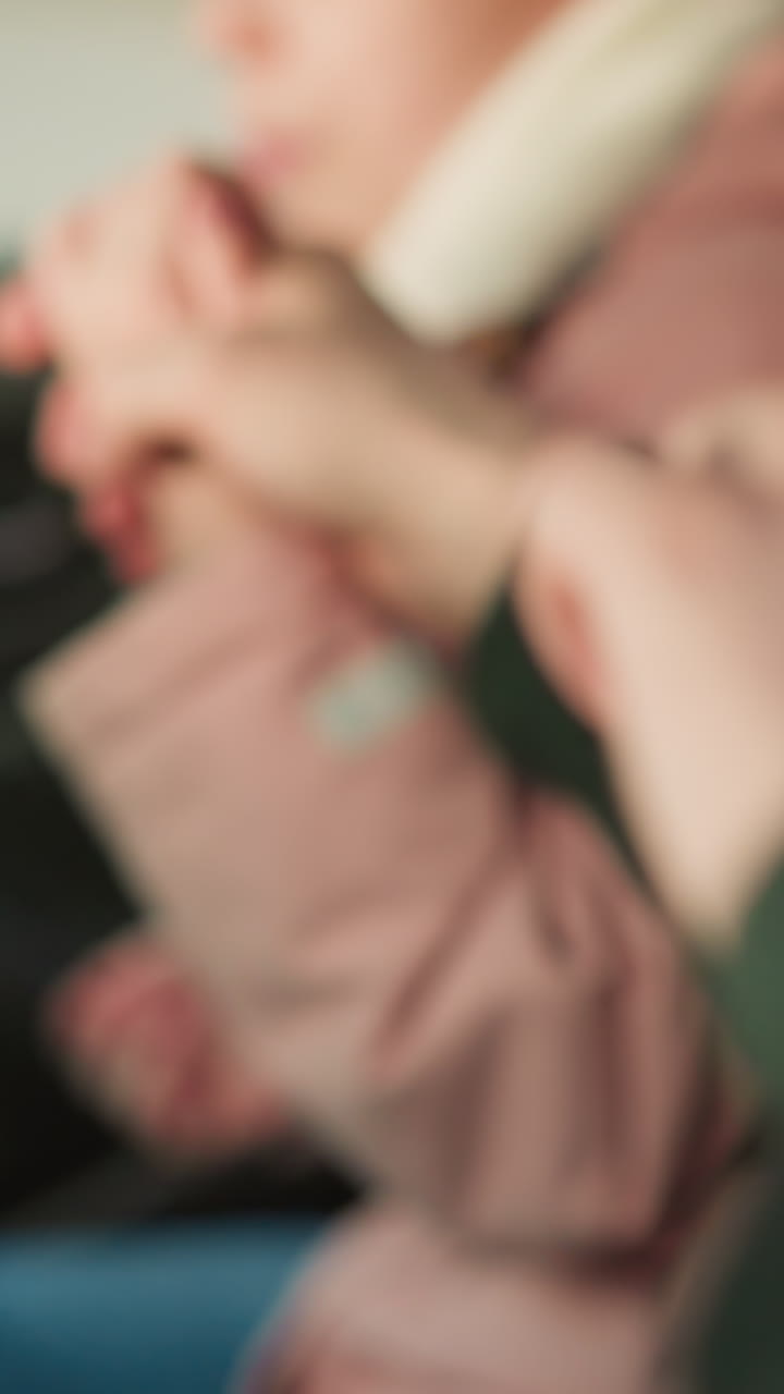 un primer plano de un hombre y una joven sentados en un coche, tomados de la mano y moviéndose alegremente juntos. la chaqueta rosa de la chica y la chaqueta verde del hombre son visibles, enfatizando un momento de conexión