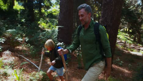 padre y hijo caminando con un palo de madera en el bosque