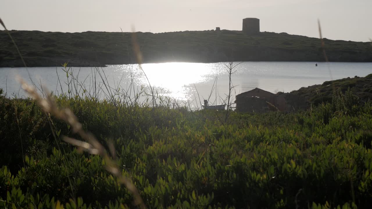Sunlit coastal scene at Torre De Sanitja, Puerto De Sanitja, with a historic tower view