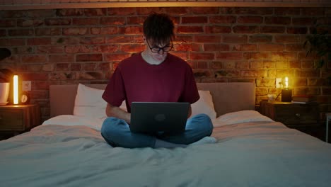 hombre trabajando en la computadora portátil en la cama por la noche