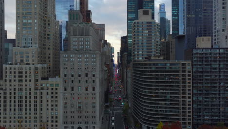 Los-Delanteros-Vuelan-Al-Espacio-Entre-Los-Edificios-Altos-Que-Rodean-El-Parque-Central.-Vuela-Sobre-La-Amplia-Avenida,-Las-Luces-Rojas-De-Freno-De-Los-Autos.-Manhattan,-Ciudad-De-Nueva-York,-Estados-Unidos