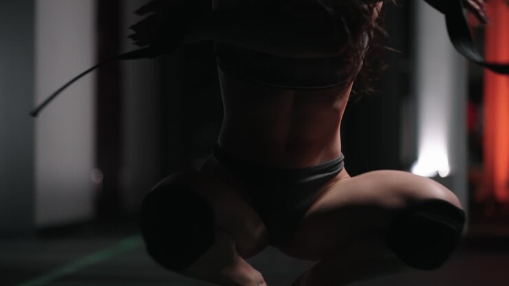 A sexy athletic woman in lingerie dances wet in oil in the gym near the gym near the gym benches and barbells.