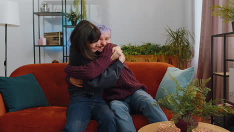 lesbian women family couple watching tv, celebrating success, winning, good news, lottery luck home