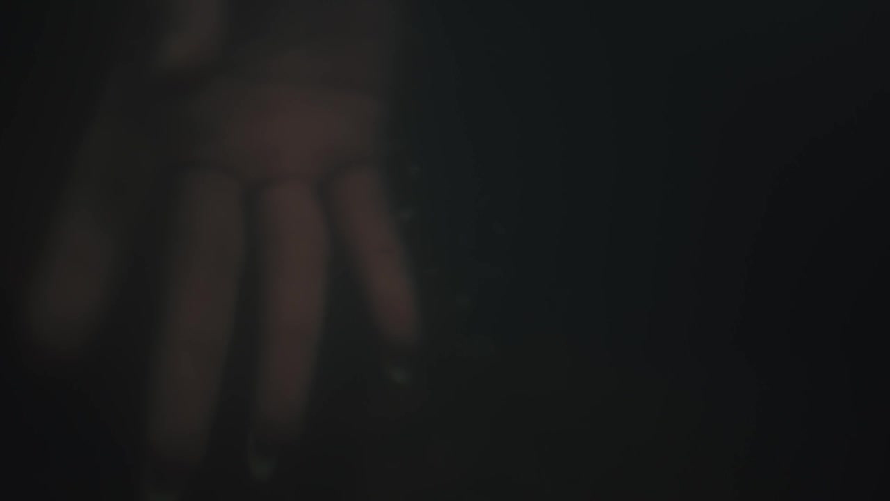 Primo piano della mano di una persona in movimento con un'illuminazione scura e suggestiva