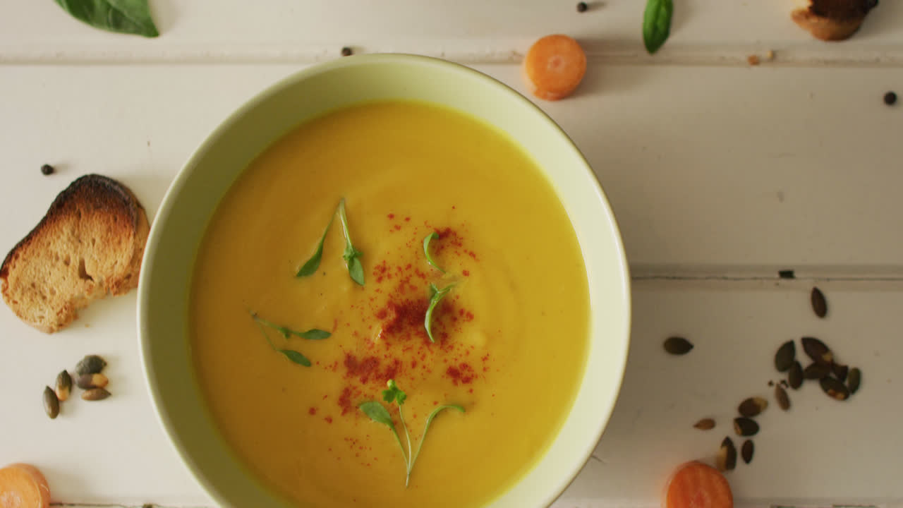 video de sopa de verduras e ingredientes sobre una superficie blanca