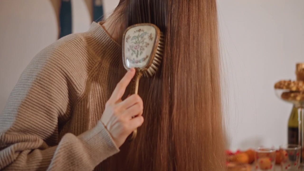 Woman cares herself. Woman gently arranges her flowing hair. Calm woman primping her lengthy hair in cozy environment. Serene woman tenderly fixing her extended hair in peaceful home setting