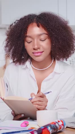 young smart african american woman student reading book with pencil in hand