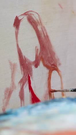 artist draws woman in red dress in studio closeup. man makes acrylic paint strokes on canvas creating art workshop. master at painting in shop