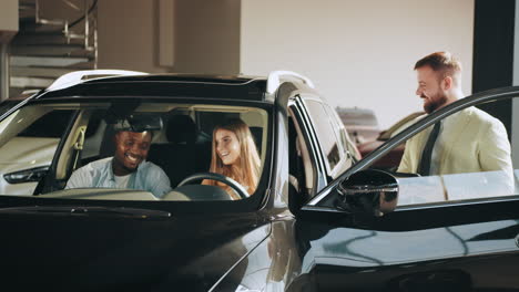 happy family test driving a new suv at a car dealership