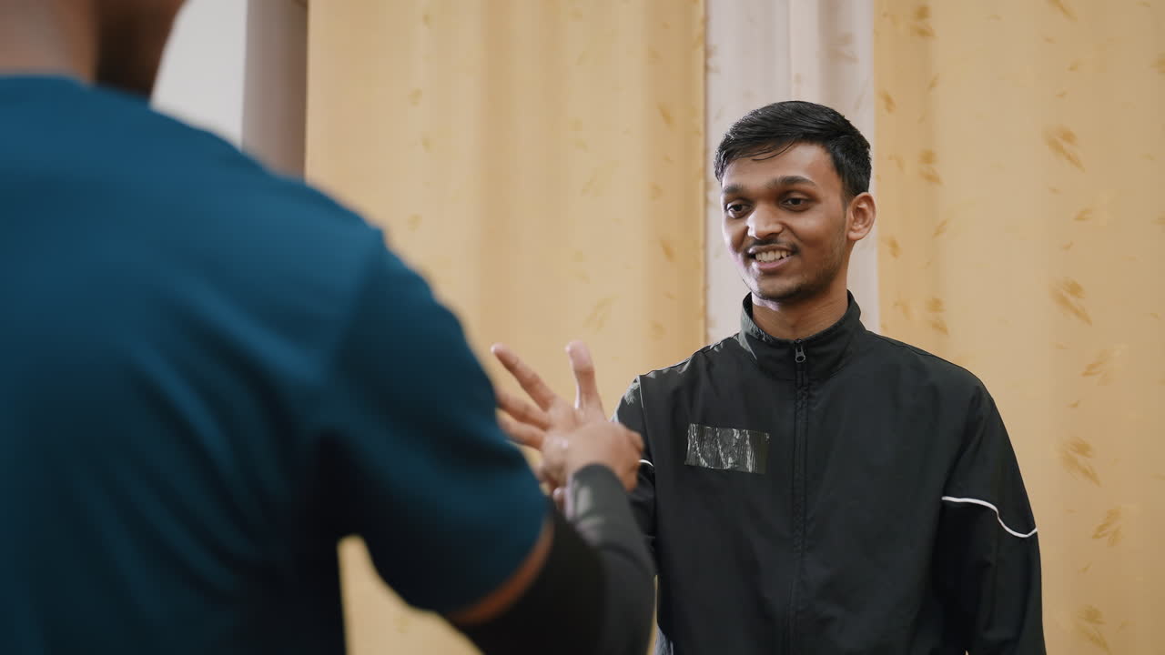 Close up rear view of person playing hand trick with sibling indoors, both smiling and enjoying fun moment, showcasing laughter, friendly competition, youthful energy, and happy connection