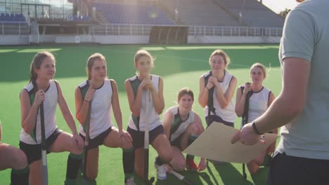 hockey coach explaining game plan with female players on the field