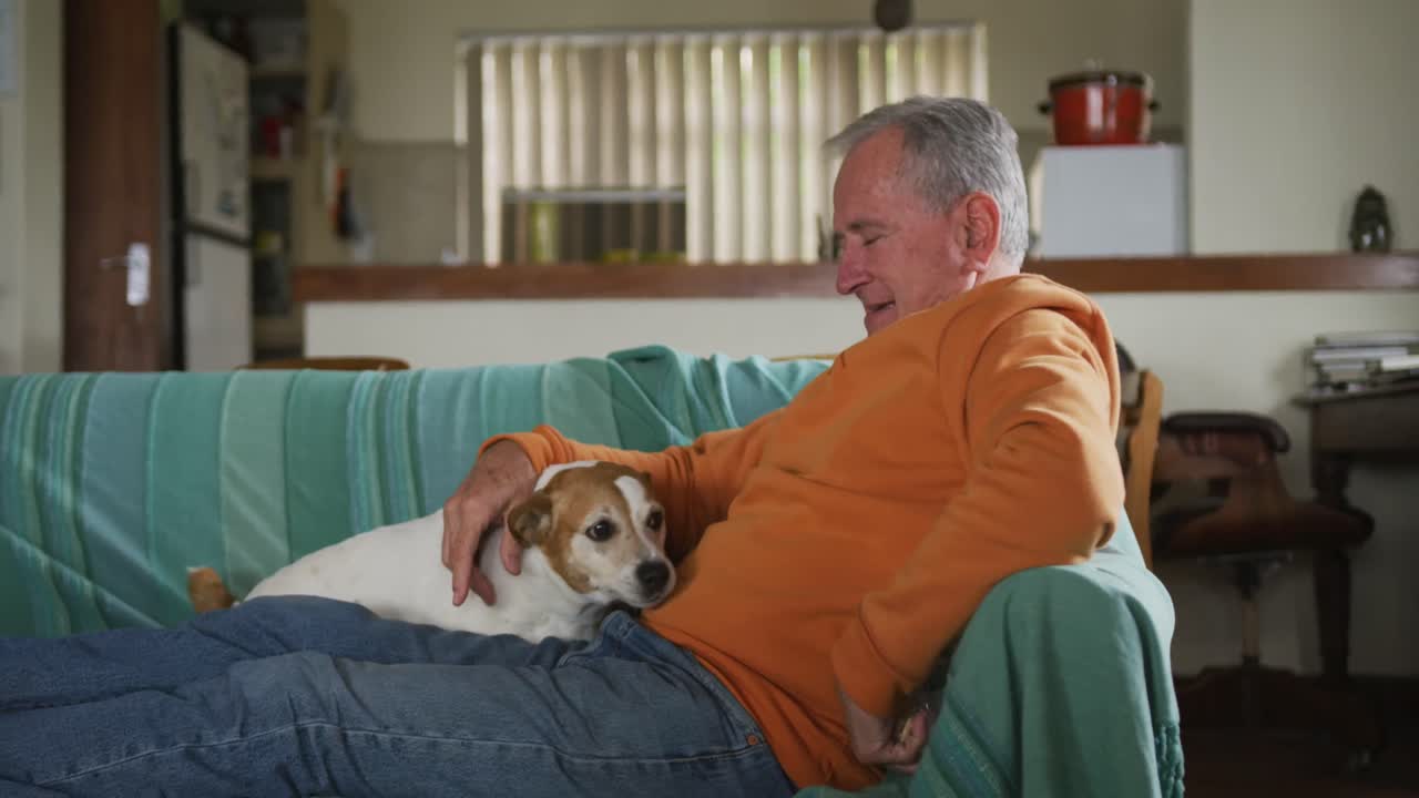 집 에서 개 와 함께 노인 이 놀고 있다