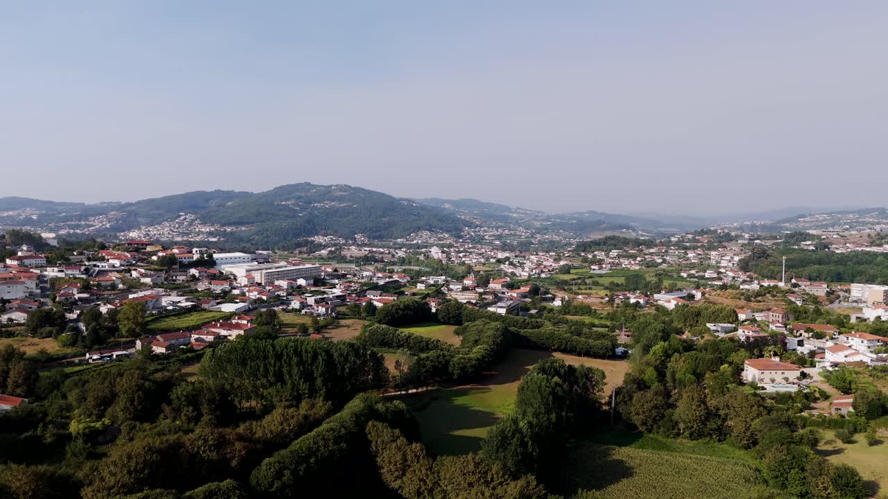 Drone view of Vizela city in Portugal with green hills, houses, and distant mountains