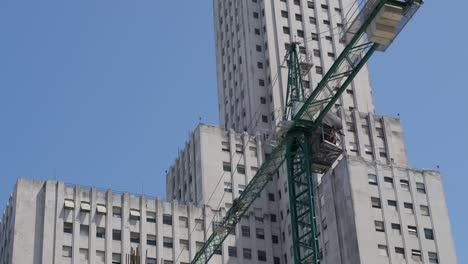 imágenes aéreas dinámicas capturando una grúa en movimiento, ocupada construyendo un edificio en el corazón de buenos aires, mostrando el crecimiento y desarrollo urbano en el bullicioso centro de la ciudad durante el día
