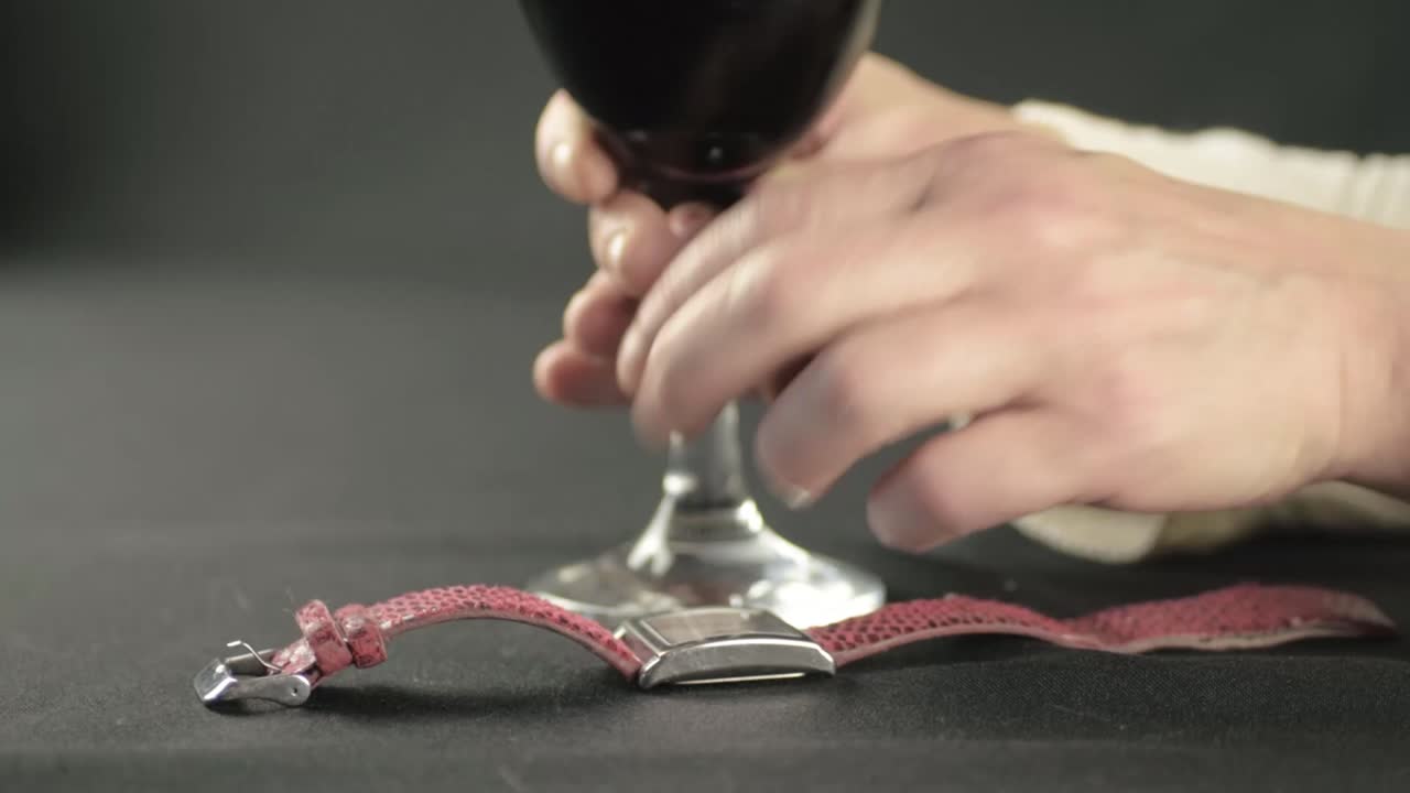 Hand with glass of wine checking wristwatch close up shot