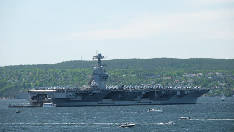 boats cruising around american military ship uss gerald ford in oslo fjord in norway