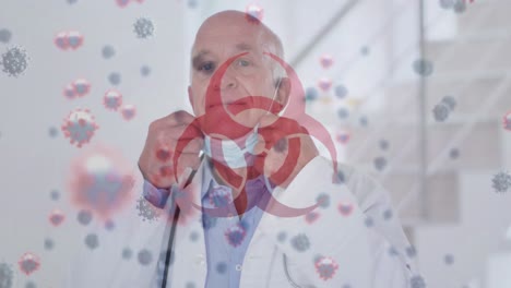 símbolo de peligro biológico y células de covid-19 flotando contra el médico senior masculino bajando su máscara facial