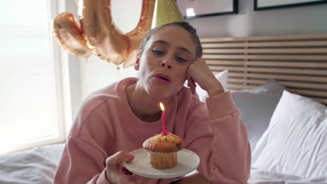 disappointed woman blowing out the candle on the birthday cupcake