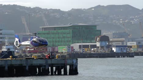 a shot on the wellington waterfront of a helicopter on a wharf taking off and leaving frame