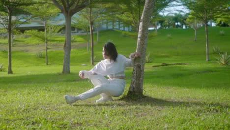 Young-Hipster-Woman-Sit-And-Lean-On-A-Tree-At-Summer