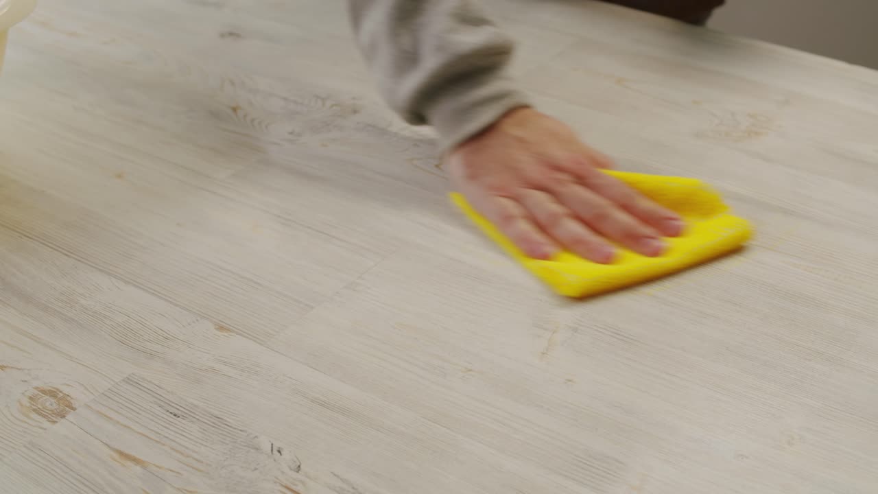 Close-Up of Hand Spraying and Wiping Wooden Surface