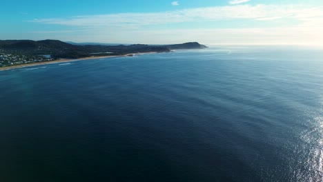 Landscape drone aerial of scenic Pacific ocean sea with swell lines and waves rolling to shoreline and residential housing from Terrigal Wamberal Central Coast Australia nature travel tourism holidays