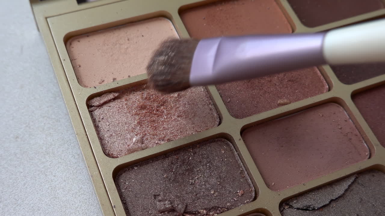Make-up brush picking up a sparkling colour from an eyeshadow palette