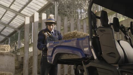 man working loading the hay on the box of his off-road vehicle to feed the animals