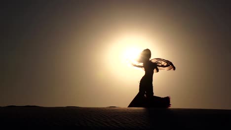 silhouette of a belly dancer in the desert at sunset