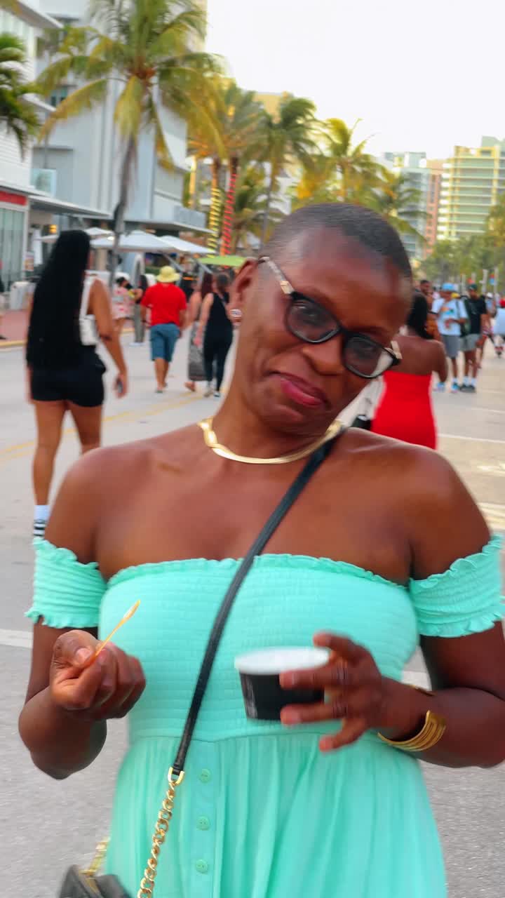 Miami, USA, 4 agosto 2025: Donna sorridente in abito turchese in una strada assolata a Miami. Ritratto di donna felice in abito turchese che cammina su Ocean Drive con palme sullo sfondo.