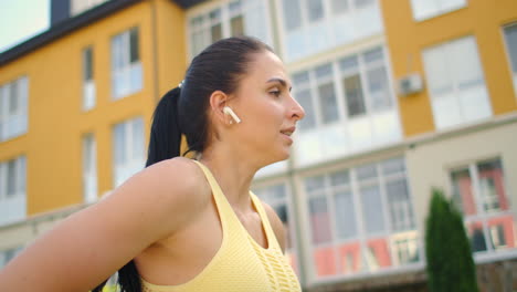 yoga classes with headphones listening to music in the city park in the summer. slopes and warm-up before training. a sports girl on the grass does yoga.