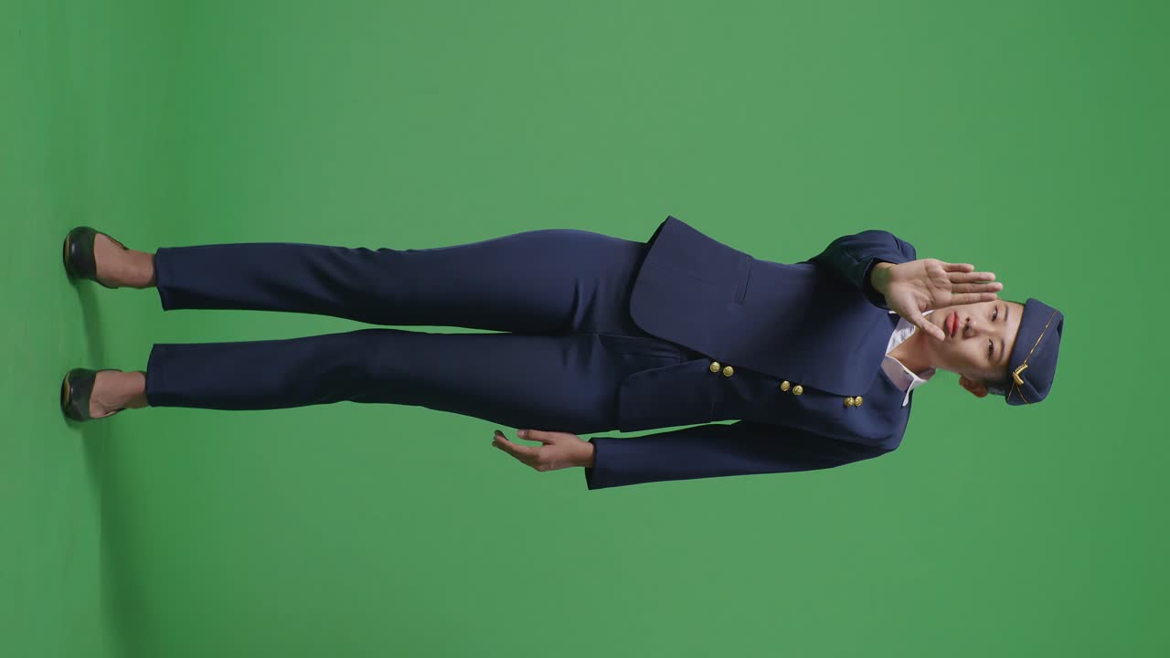 아시아 여성 승무원이 카메라를 바라보고 녹색 스크린 배경 스튜디오에서 손 표시 없이 불쾌감을 표합니다.