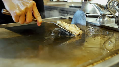 Ein-Japanischer-Koch-Bereitet-Gebratenes,-Geschnittenes-Schweinefleisch-Auf-Einem-Kochherd-Zu,-Um-Die-Gäste-In-Einem-Ambiente-Restaurant-Zu-Speisen