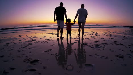 family walking on a beach at sunset
