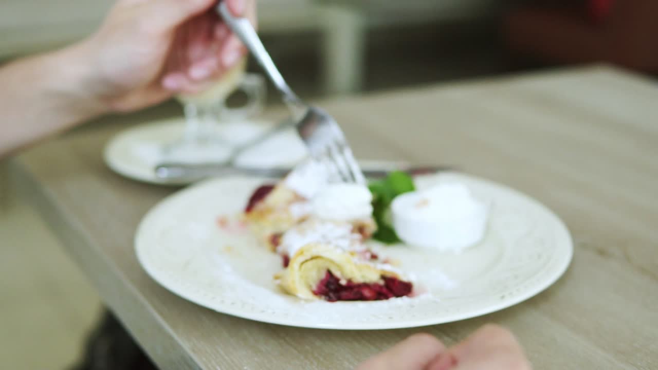 Unrecognizable man in white t-shirt taking desert strudel at the restaurant using fork and knife. Slow Motion shot