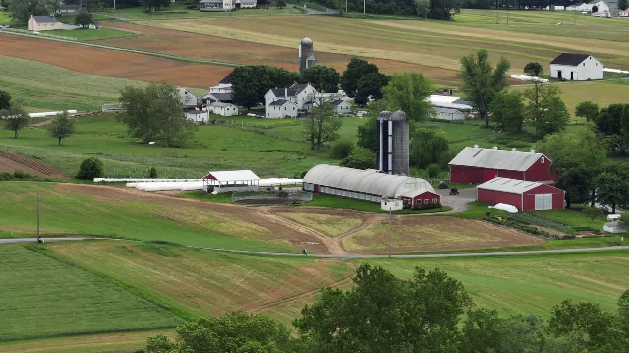 Picturesque farm landscape with red barns and green fields. This rural setting showcases America’s agricultural heritage and natural beauty, evoking a sense of peace. Aerial view.