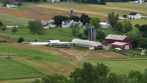 picturesque farm landscape with red barns and green fields. this rural setting showcases america’s agricultural heritage and natural beauty, evoking a sense of peace. aerial view.