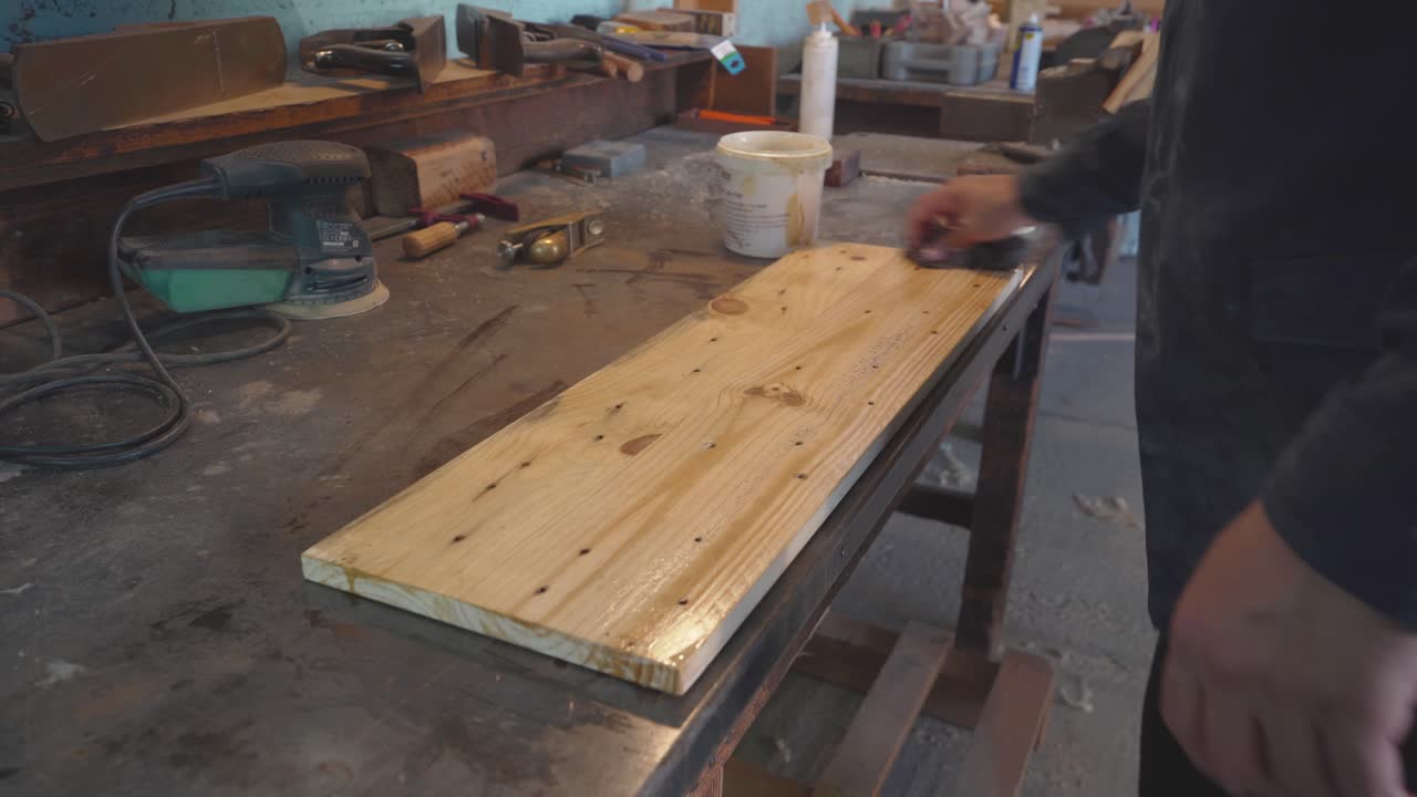 artista frotando aceite en una estantería de madera reciclada
