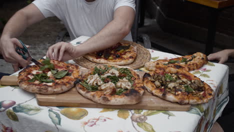 chef cuts slices of pizza and gives to people sitting at the table