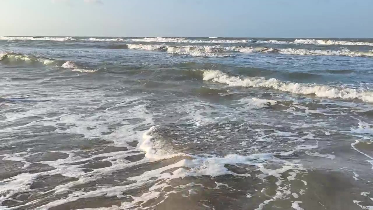 Dolci onde dell'oceano che si infrangono su una spiaggia sabbiosa.