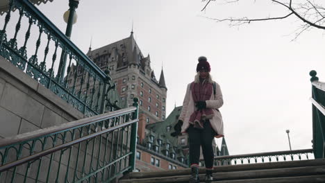 girl walking down the stairs near chateau frontenac hotel at wintertime in old quebec, quebec, canada