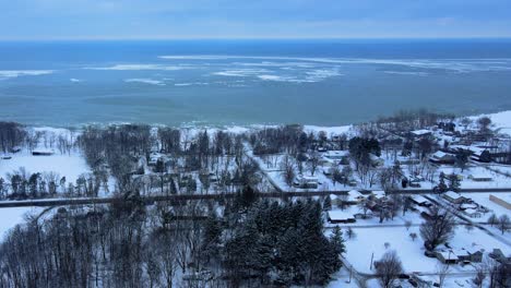 Drohnenaufnahmen-Aus-Der-Luft-Einer-Kleinen-Stadt-Mit-Blick-Auf-Einen-Zugefrorenen-Eriesee-Im-Westlichen-Bundesstaat-New-York-Im-Winter-Mit-Frischem-Schneefall-Und-Eis